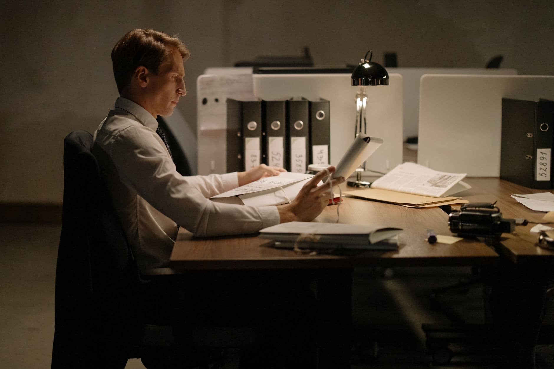 A business owner sitting at a desk late at night reviewing financial paperwork, showing the toll of burnout on decision-making
