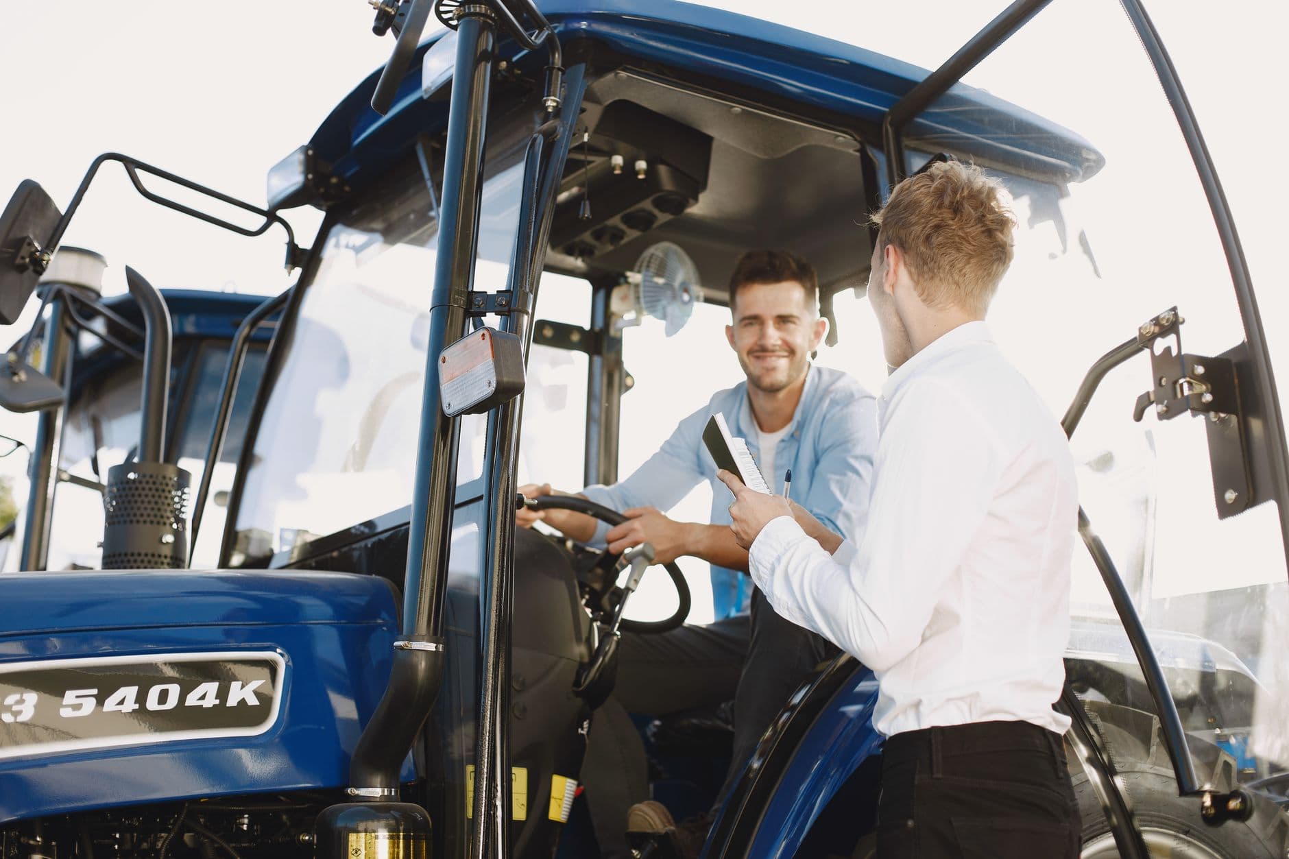 Farmer reviewing financial paperwork near a tractor in a field