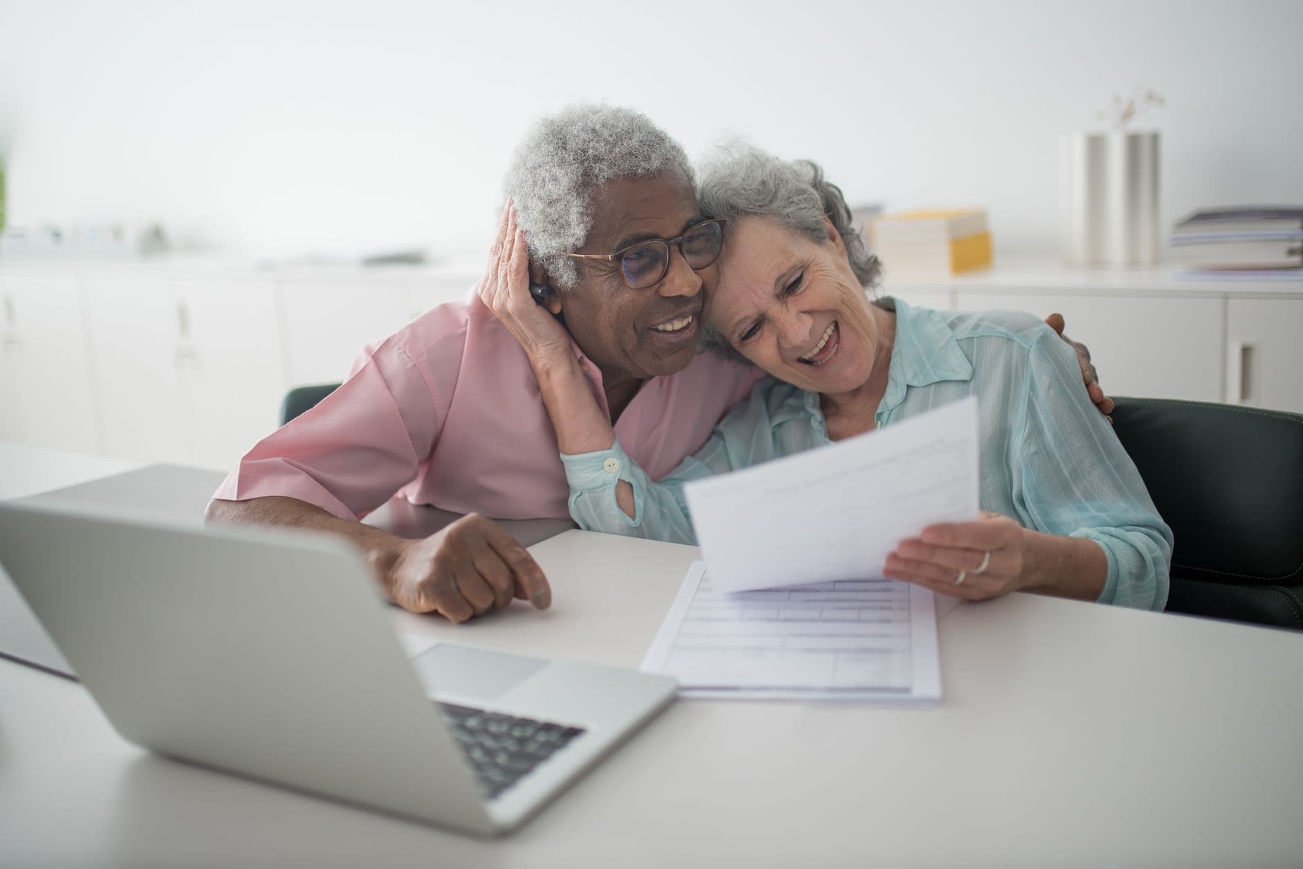 Senior couple sitting at a kitchen table reviewing financial documents together